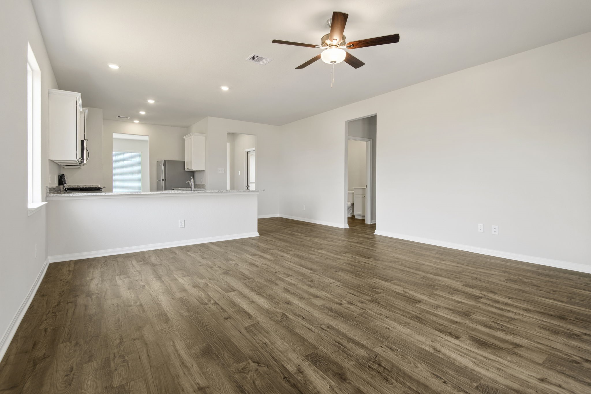 708 Jasmine Ridge Lane Waller, TX 77484 - Photo 10 of 12 a view of a kitchen with wooden floor and a ceiling fan