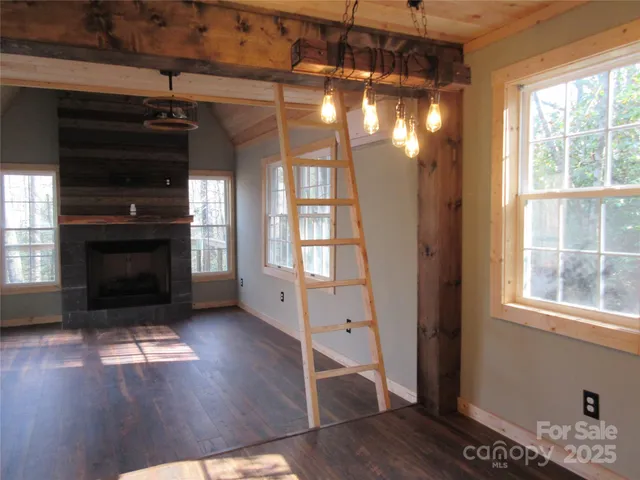 a view of a livingroom with wooden floor a fireplace and window