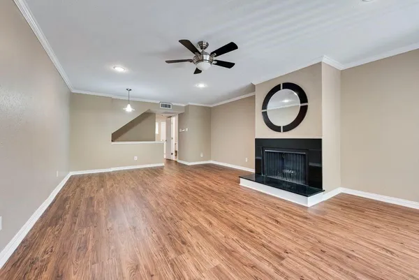a view of a livingroom with a fireplace a ceiling fan and wooden floor