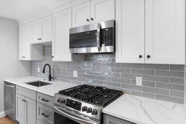 a kitchen with stainless steel appliances a sink a stove and cabinets