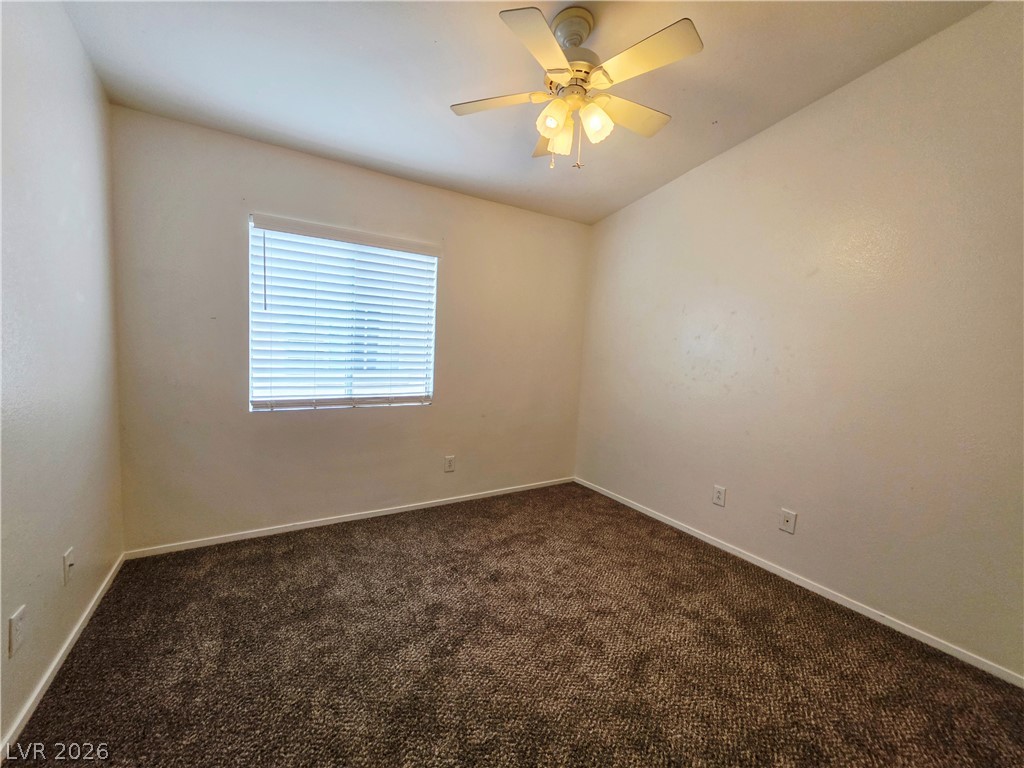 1571 Rusty Ridge Lane Henderson, NV 89002 - Photo 20 of 26 A well-proportioned bedroom awaits personalization, offering a ceiling fan for comfort and a window for natural light.