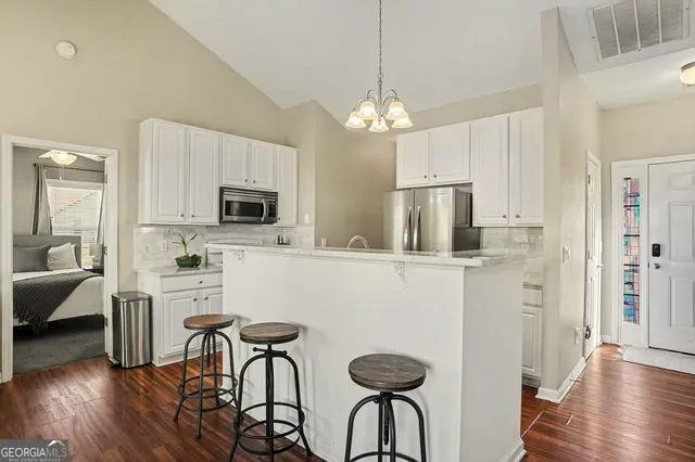 a kitchen with stainless steel appliances a dining table chairs stove refrigerator and cabinets