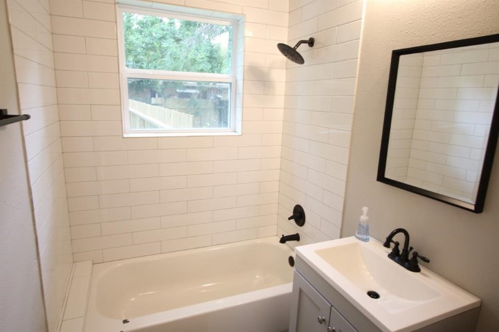 2612 Isabella Street Houston, TX 77004 - Photo 21 of 34 a bathroom with a white bath tub sitting next to a white sink and a window
