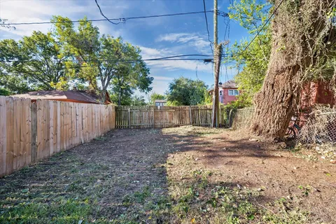 a view of a backyard with wooden fence and a large tree