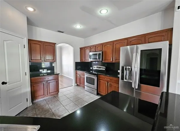a kitchen with granite countertop a stove a sink and a refrigerator