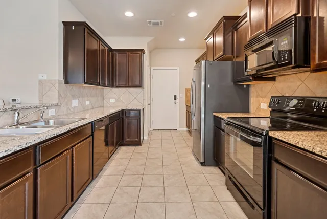 a kitchen with stainless steel appliances granite countertop a sink stove and refrigerator