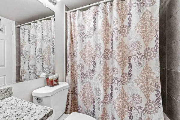 a bathroom with a toilet sink and a shower curtain