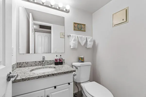 a bathroom with a granite countertop toilet sink and mirror