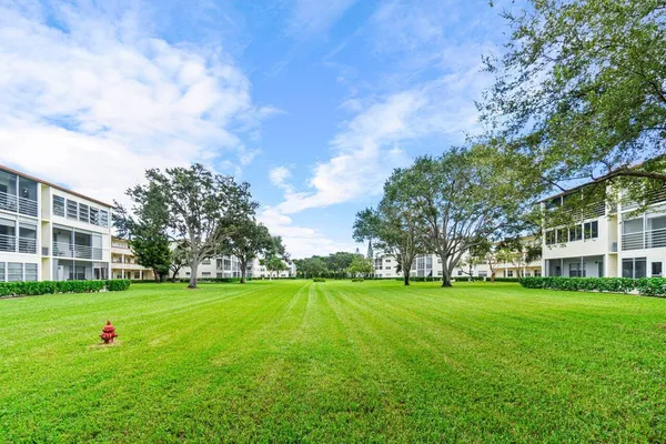 a view of a building with a big yard and large trees