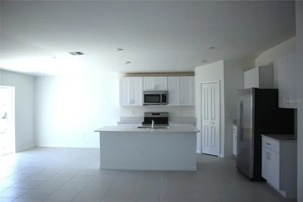a living room with stainless steel appliances kitchen island a large counter top space and a window