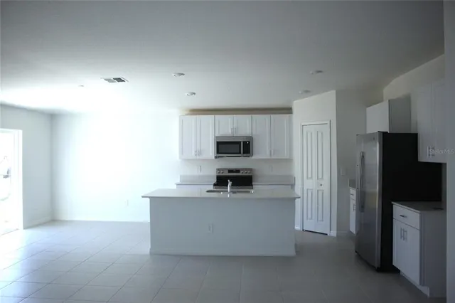 a living room with stainless steel appliances kitchen island a large counter top space and a window