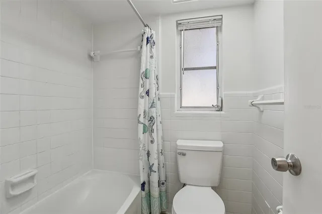 a white toilet sitting next to a bath tub