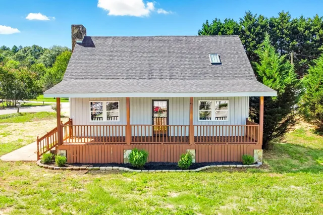 a view of a house with wooden deck and a big yard
