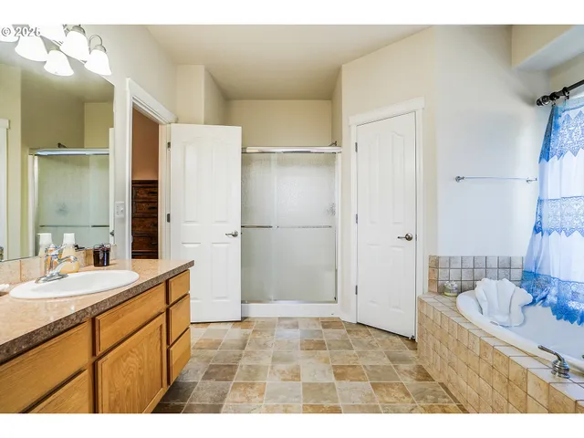 a bathroom with a sink vanity granite tub shower and a mirror