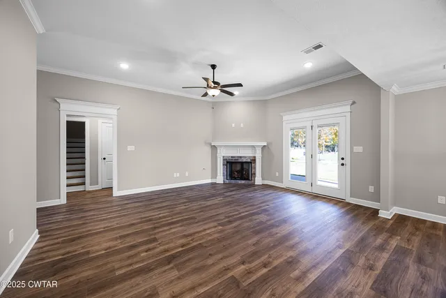 an empty room with wooden floor fireplace and windows