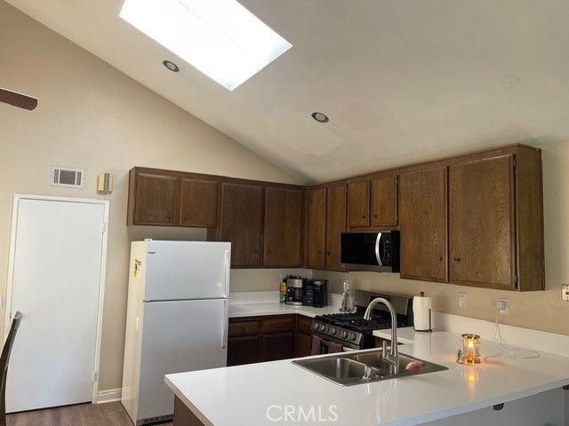 6435 Melray Street Moorpark, CA 93021 - Photo 39 of 41 a kitchen with a sink a refrigerator and a stove top oven with wooden floor
