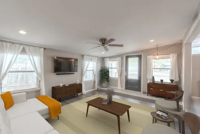 a living room with furniture a flat screen tv and a large window