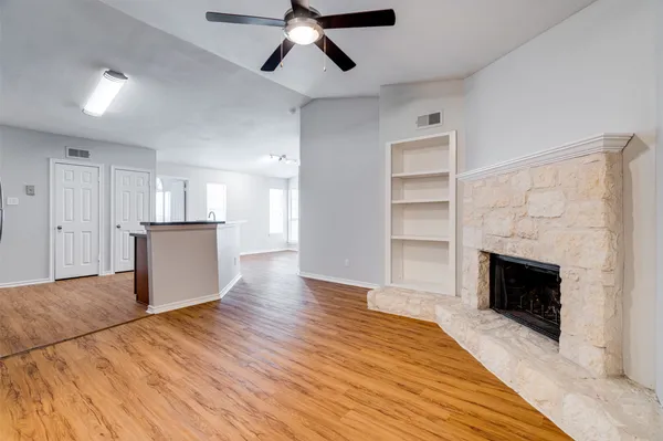 a view of a livingroom with wooden floor and a kitchen