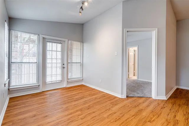 a view of empty room with wooden floor and fan