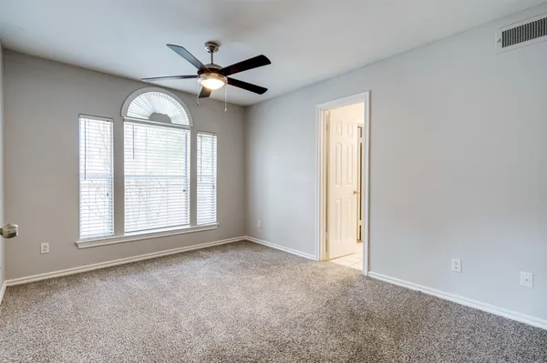 an empty room with windows and fan