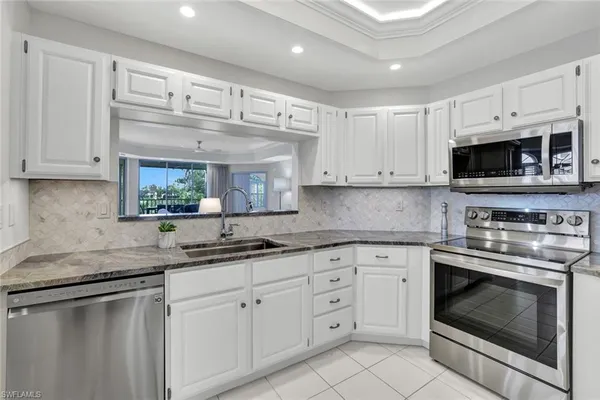 a kitchen with stainless steel appliances granite countertop a sink a stove a microwave and cabinets