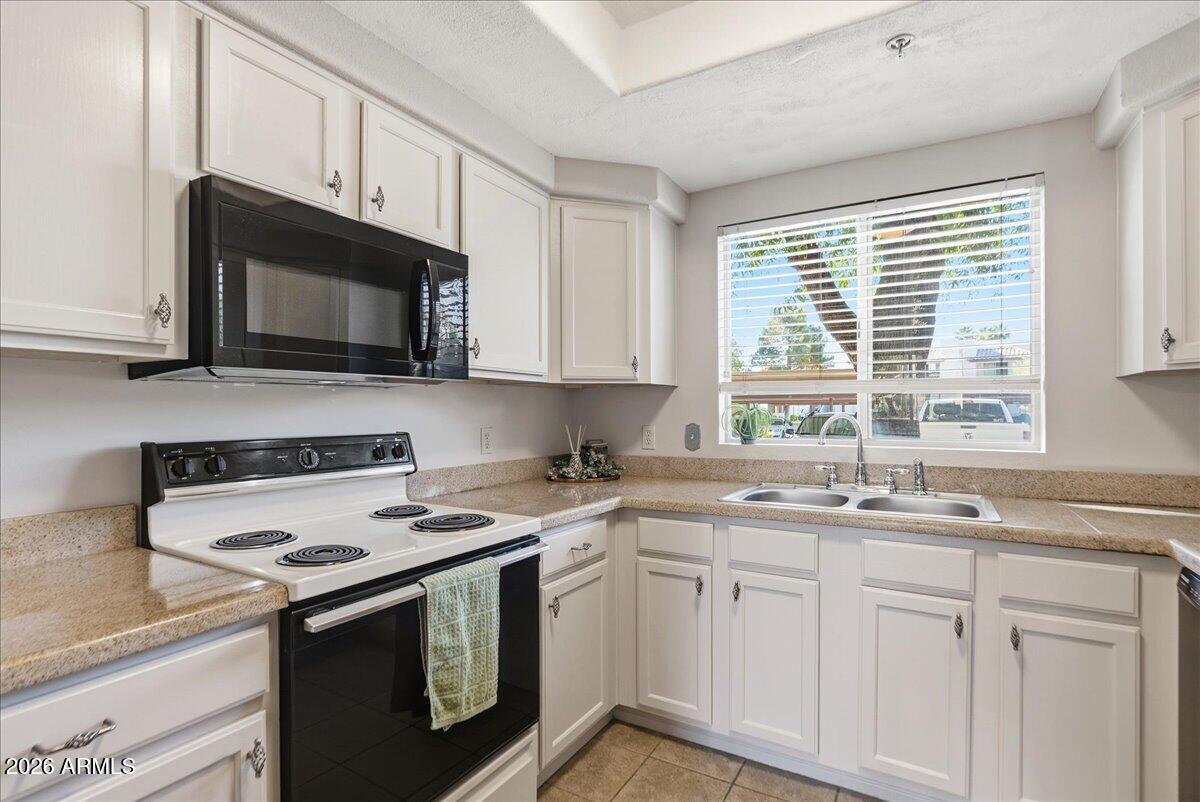 1825 West Ray Road, Unit 1106 Chandler, AZ 85224 - Photo 6 of 62 a kitchen with stainless steel appliances granite countertop white cabinets a sink and a stove