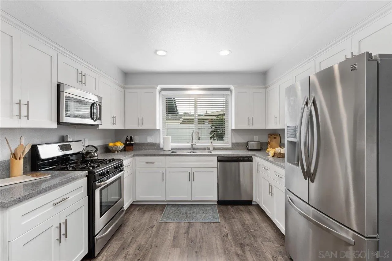 14050 Halper Road Poway, CA 92064 - Photo 9 of 29 a kitchen with white cabinets stainless steel appliances a sink and a window