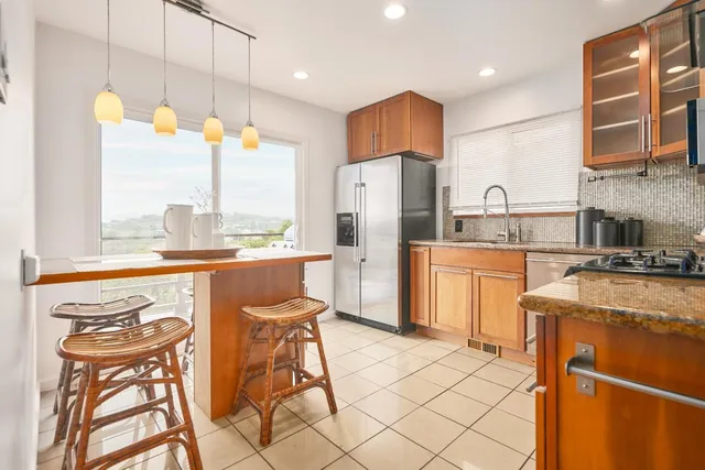 a kitchen with stainless steel appliances granite countertop a stove a sink a refrigerator and a dining table with granite countertops