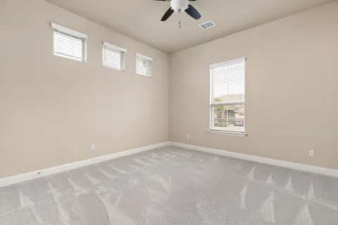 an empty room with windows and fan