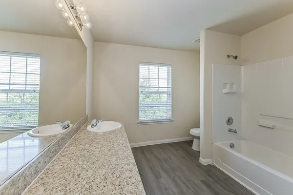 a spacious bathroom with a granite countertop sink a toilet and bathtub