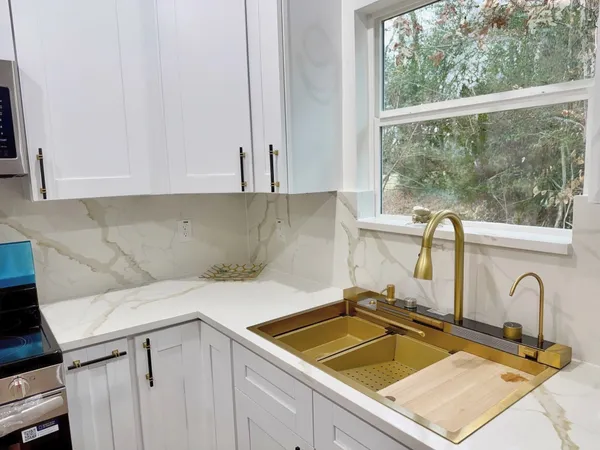 a kitchen with a sink a stove a refrigerator and white cabinets
