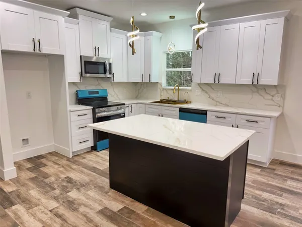 a kitchen with stainless steel appliances kitchen island granite countertop a sink dishwasher a stove and a refrigerator with wooden floor