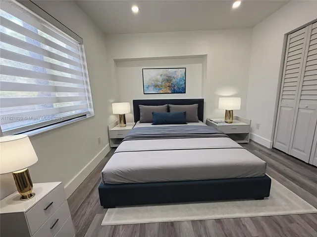 a bedroom with a bed and a lamp on dresser