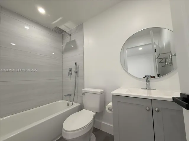 a bathroom with a toilet a sink a mirror a bathtub and vanity