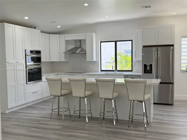 a kitchen with stainless steel appliances granite countertop a table chairs refrigerator and sink