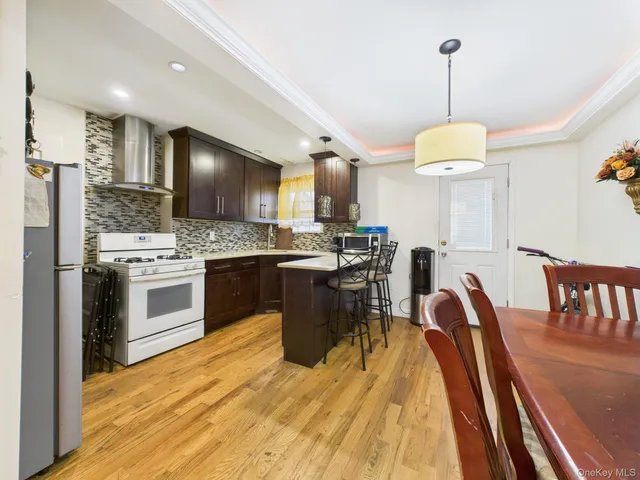 a kitchen with stainless steel appliances granite countertop a stove top oven a sink dishwasher a dining table and chairs with wooden floor