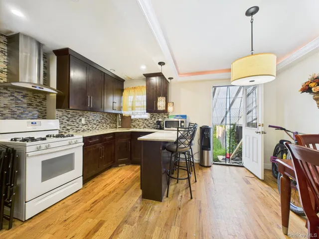 a kitchen with stainless steel appliances granite countertop a kitchen island hardwood floor sink stove dining table and chairs