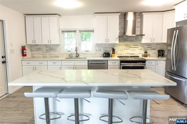 a kitchen with stainless steel appliances kitchen island granite countertop a table chairs sink refrigerator and cabinets