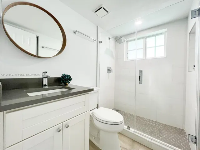 a bathroom with a toilet a sink a mirror and a shower
