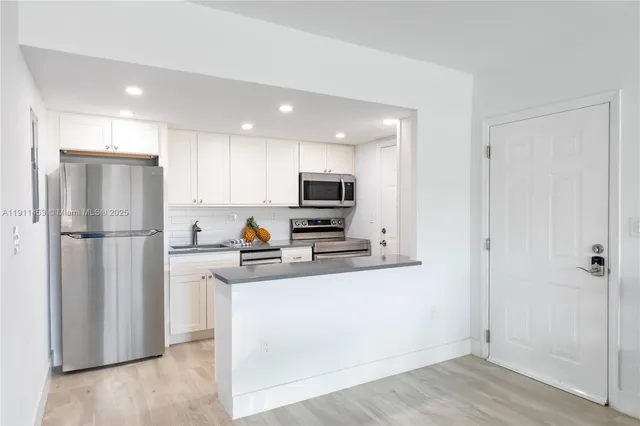 a kitchen with a refrigerator a stove top oven a sink and cabinets