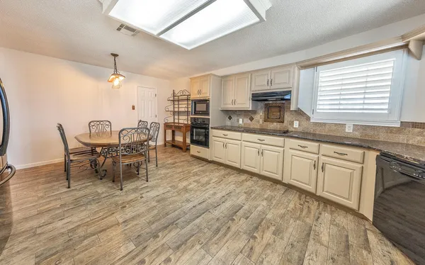 a kitchen with kitchen island granite countertop a sink cabinets and wooden floor