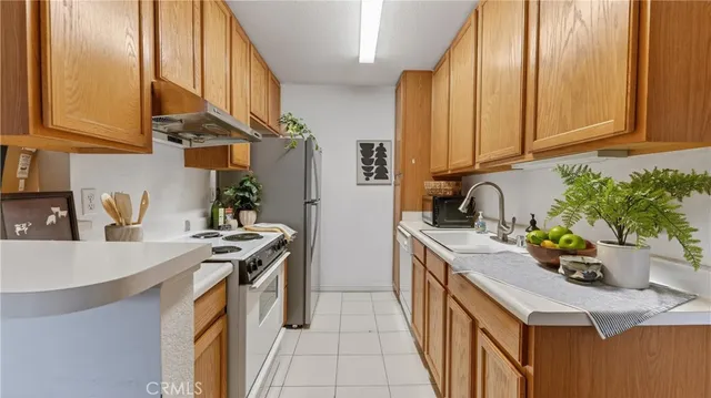 a kitchen with stainless steel appliances a stove a sink and a refrigerator with wooden floor