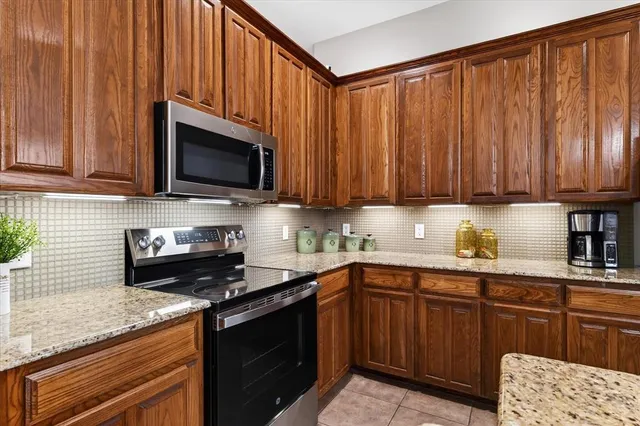 a kitchen with granite countertop wooden cabinets and stainless steel appliances