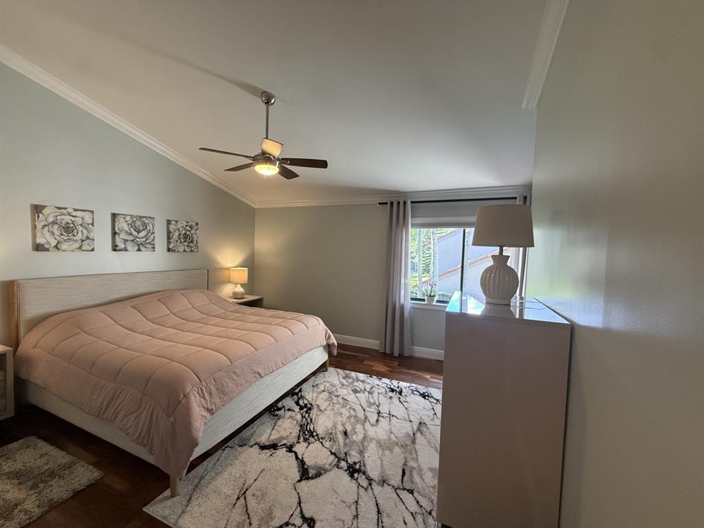 5560 Coach House Circle, Unit C Boca Raton, FL 33486 - Photo 20 of 31 a bedroom with a large bed and a chandelier