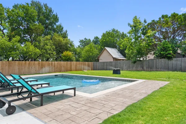 a view of a backyard with lawn chairs and wooden fence