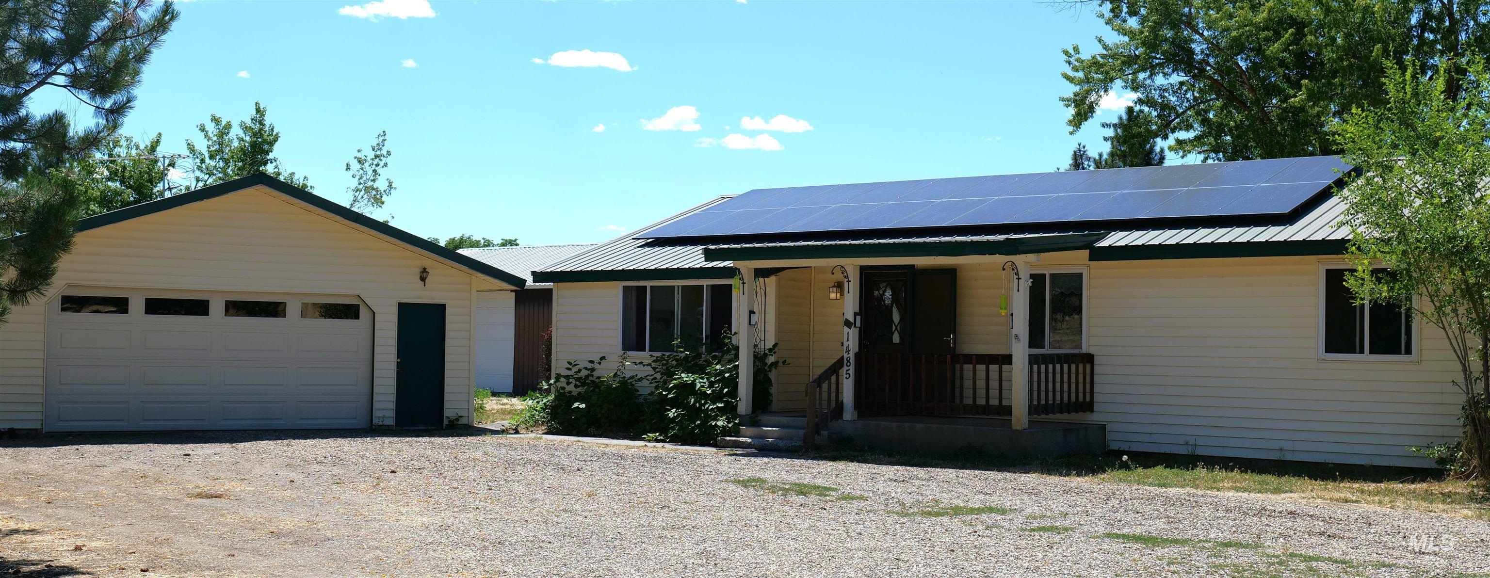 1485 East 9th Street Weiser, ID 83672 - Photo 1 of 18 Ranch-style residence featuring light-colored siding, a metal roof with integrated solar panels, and a covered front porch with railings