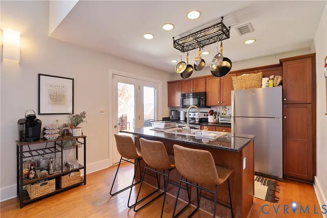 a kitchen with stainless steel appliances granite countertop a stove refrigerator dining table and chairs