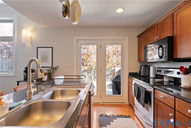 a kitchen with stainless steel appliances granite countertop a sink a stove and a refrigerator with wooden floor