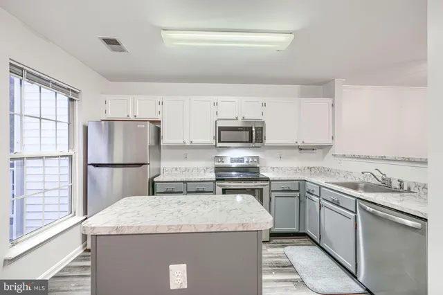 a kitchen with kitchen island a sink stove and refrigerator