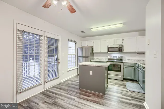 a kitchen with stainless steel appliances granite countertop a stove top oven a sink dishwasher a refrigerator and white cabinets